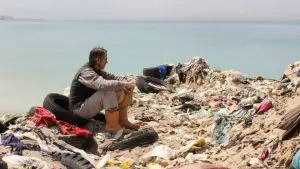 Jeremy Irons sentando com lixo em volta