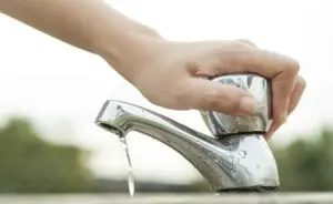 mão fechando torneira