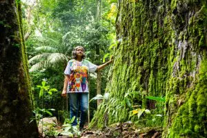 A-advogada-e-ativista-Claudelice-dos-Santos-aos-pés-da-Majestade-árvore-mãe-das-castaheiras-da-região-segundo-Zé-Claudio-e-Maria-créditoThom-Flint-CAFOD-768x512