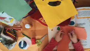 Mãos de uma criança fazendo um artesanato de papel