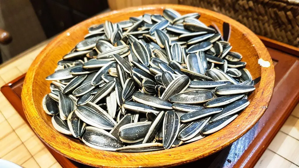 Sementes de girassol cruas em tigela de madeira sobre fundo claro