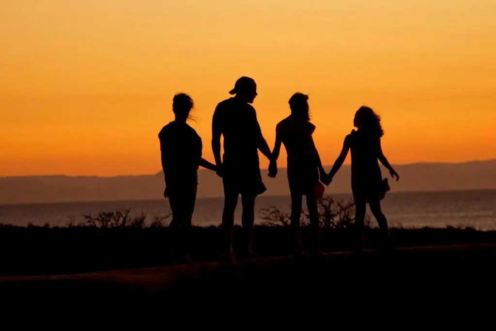 Pessoas de mãos dadas simbolizando união, apoio e laços sociais fortes para ser feliz