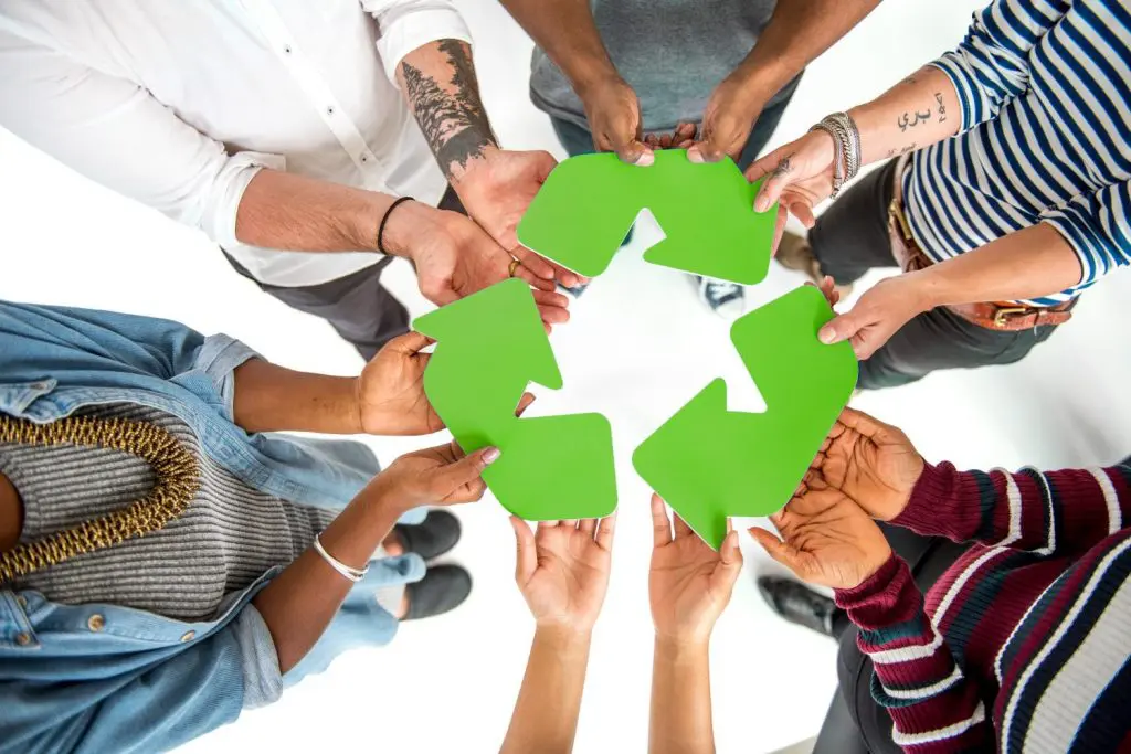 Pessoas unidas segurando o símbolo da reciclagem, representando a importância da responsabilidade ambiental individual e das ações coletivas para um futuro sustentável.